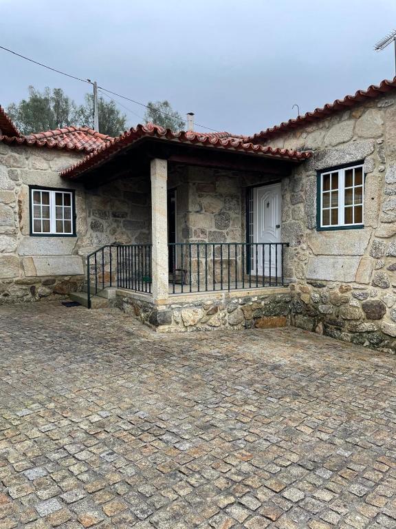 Entrada da casa com alpendre e pátio de pedra